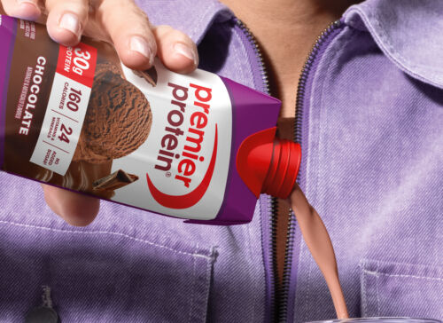 A person pouring a delicious Chocolate Premier Protein shake into a glass.