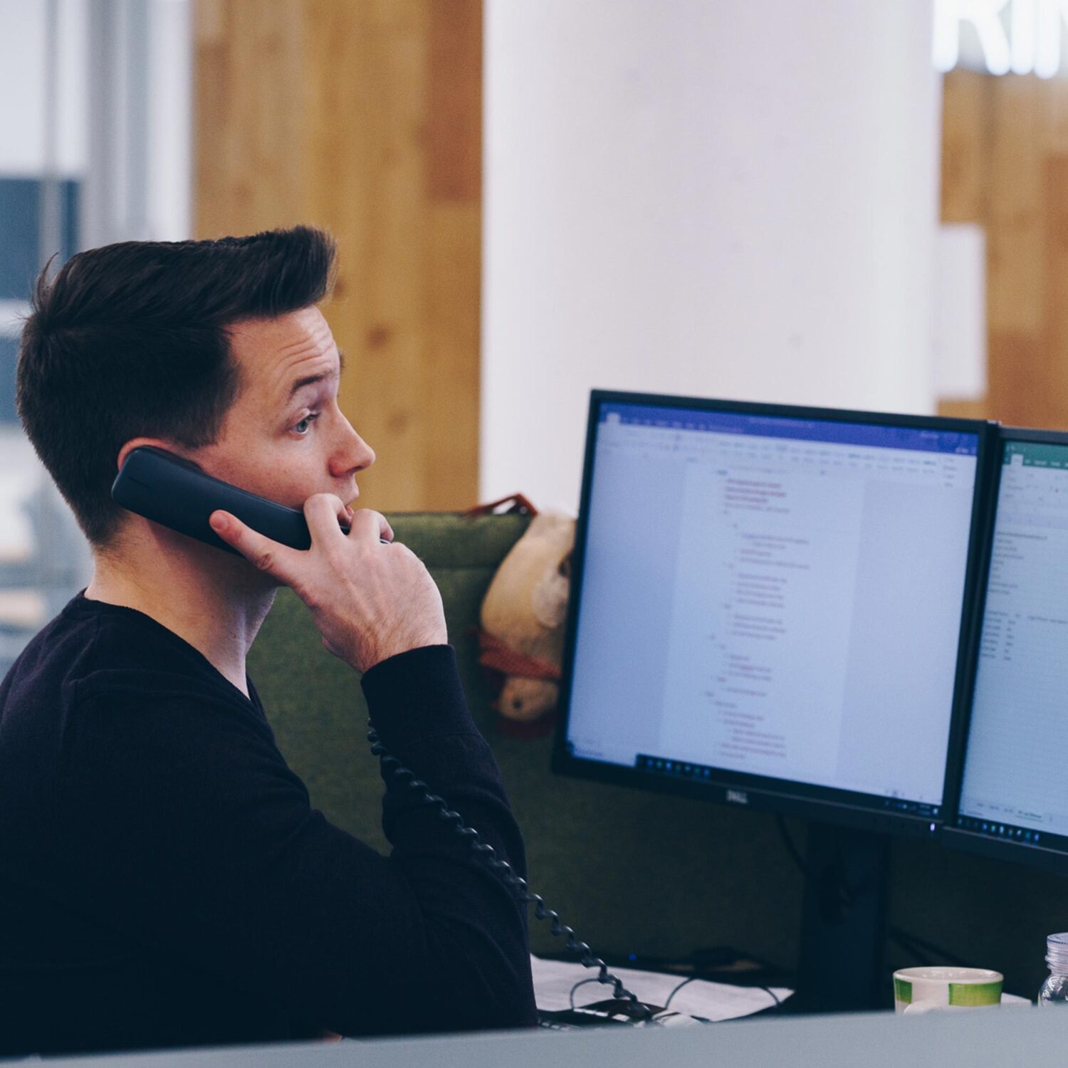 A BellRing employee at a desk, talking on a phone.
